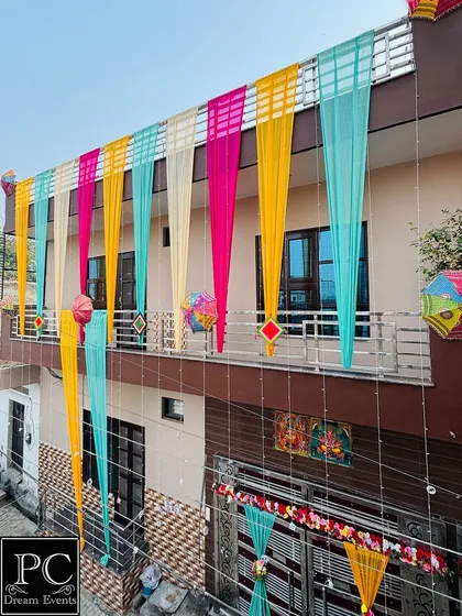 A colorful facade decoration for a pre-wedding event. I used drapes in teal, yellow, pink, and cream, accented with decorative umbrellas and hangings for a playful, festive look.