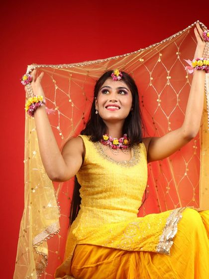 A playful shot with the dupatta. The makeup is bright and photogenic, perfect for capturing the joyful spirit of a Haldi ceremony.