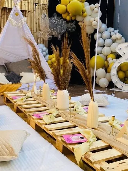 This close-up highlights the details of our popular boho-chic bachelorette party theme. We use natural textures like wooden pallets for seating, pampas grass in ceramic vases, and fun props like a diamond ring marquee light to create a trendy, relaxed vibe.