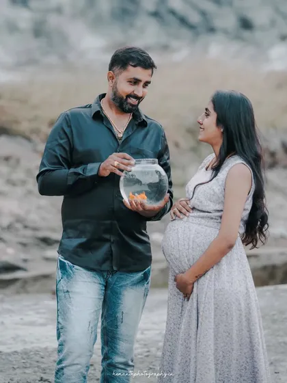 A creative and symbolic maternity photo where the couple is looking at a goldfish in a bowl, representing new life. This shows how we can incorporate unique props into your shoot.