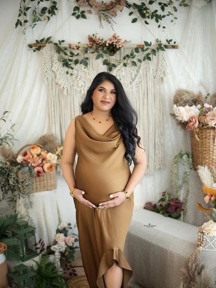 A classic three-quarter length portrait of a mother-to-be. Her hands gently cradle her baby bump, and her expression is one of serene happiness.