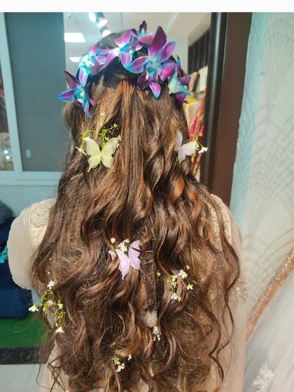A whimsical hairstyle for a pre-wedding event. I created soft waves and adorned them with fresh orchids and delicate butterfly clips for a fairytale look.