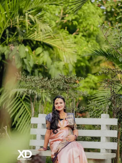 A peaceful portrait of the mother-to-be seated on a bench in a garden, surrounded by nature.