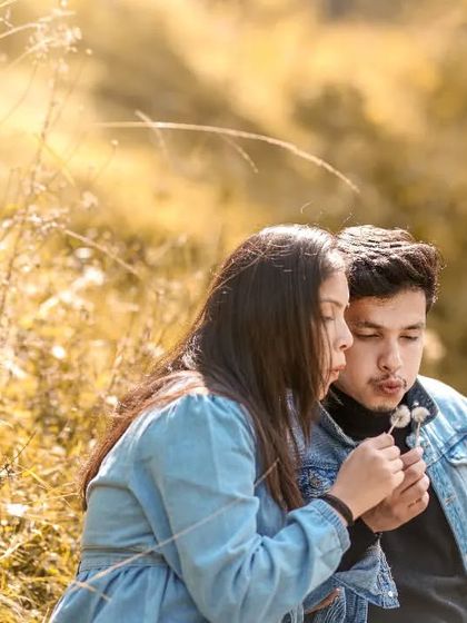 A sweet and whimsical moment of a couple blowing dandelion seeds in a golden field. This captures a simple, innocent, and romantic memory.