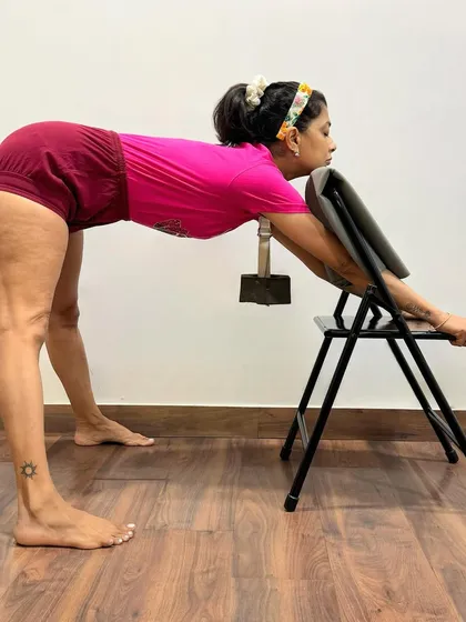 Using a chair and weight for cervical spine alignment. The weight on the C7 vertebra helps to correct its position, addressing the root cause of neck pain. This should only be attempted with a certified teacher.