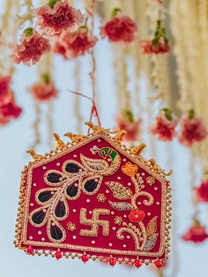 A traditional, handcrafted ornament with a swastika symbol hangs amidst floral strings. This detail adds a layer of blessing and cultural significance to the wedding decor.