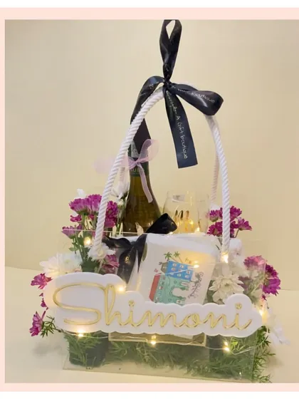 A customized acrylic basket hamper with a floral arrangement and fairy lights. The personalized nameplate makes this a truly special and modern gift.