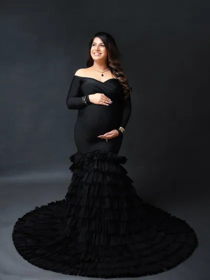 A full-length portrait showcasing a magnificent black ruffled mermaid gown. This is a perfect example of how a statement dress can create a truly unforgettable maternity photo.