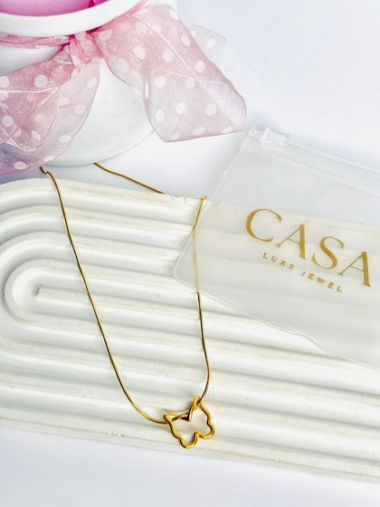 A delicate butterfly pendant necklace styled with its packaging on a white tray. This type of clean, bright photography is highly effective for e-commerce and catalogue listings.