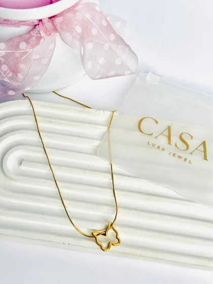 A delicate butterfly pendant necklace styled with its packaging on a white tray. This type of clean, bright photography is highly effective for e-commerce and catalogue listings.
