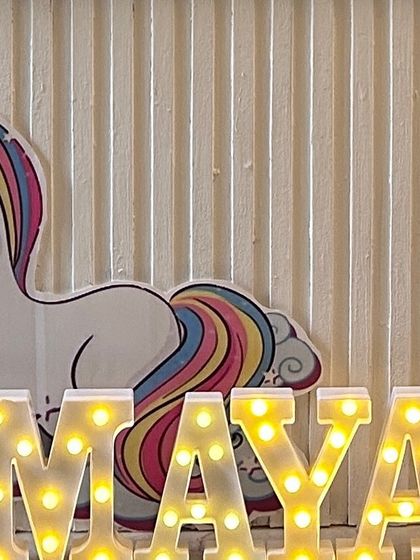 Light-up marquee letters spelling "MAYA" in front of a unicorn cutout. This personalized element is a popular addition to my birthday decoration packages.