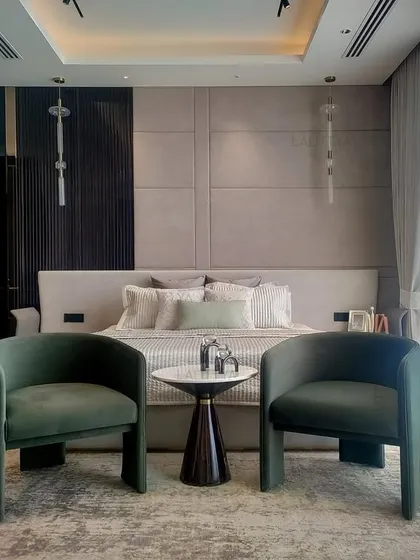 A guest bedroom designed to feel like a quiet exhale. The space is gentle and grounded, with a neutral palette, soft textures, and two comfortable green armchairs for conversation.