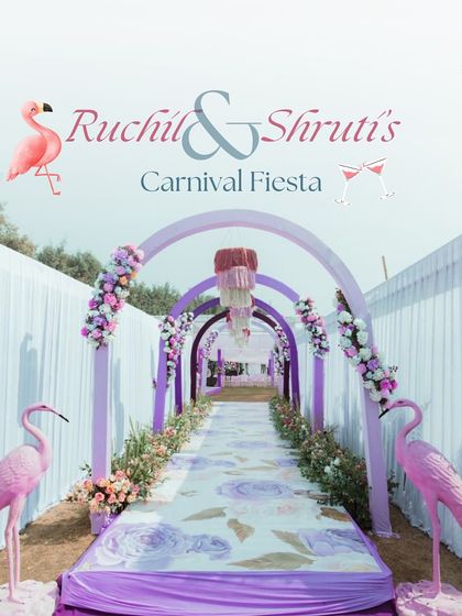 A whimsical carnival-themed entrance for a Mehendi, with pastel purple arches, floral arrangements, and flamingo statues.