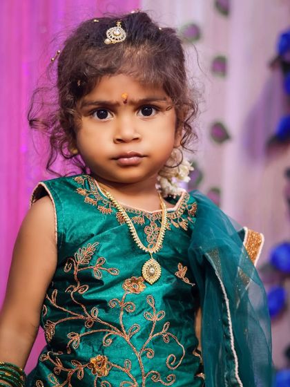 A close-up portrait of a little girl with beautiful curly hair. The simple background and soft lighting draw all the attention to her expressive eyes and sweet face.