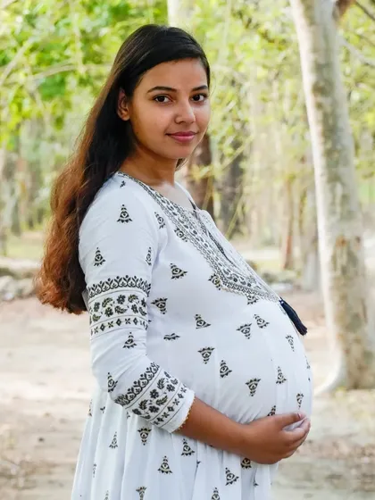 A lovely portrait of an expectant mother in a white dress, enjoying a moment in the park. We use natural settings to create a relaxed and beautiful backdrop.