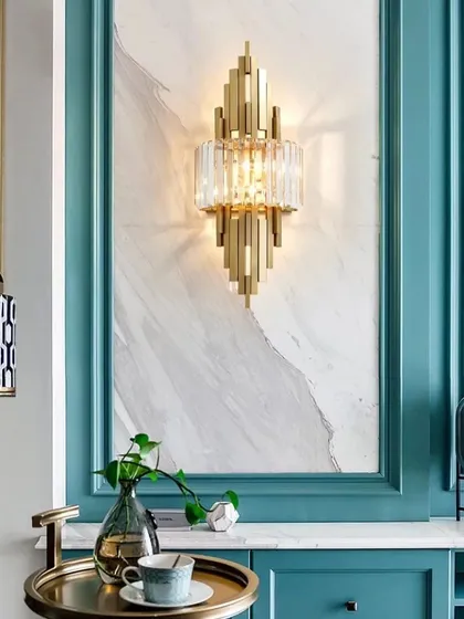 This Art Deco inspired wall sconce is a true masterpiece, combining geometric gold metalwork with brilliant crystal. It is designed to be a focal point, casting intricate patterns of light and shadow to elevate a living room or entryway.