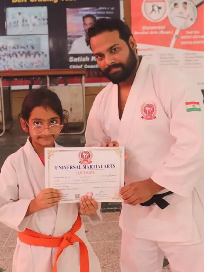 My guru, Satish Kumar, awarding a certificate to a young student after she successfully passed her belt test. Every student's progress is recognized and celebrated here.