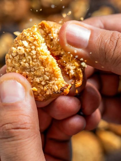 An action shot of hands breaking a cookie, showing its crumbly texture.