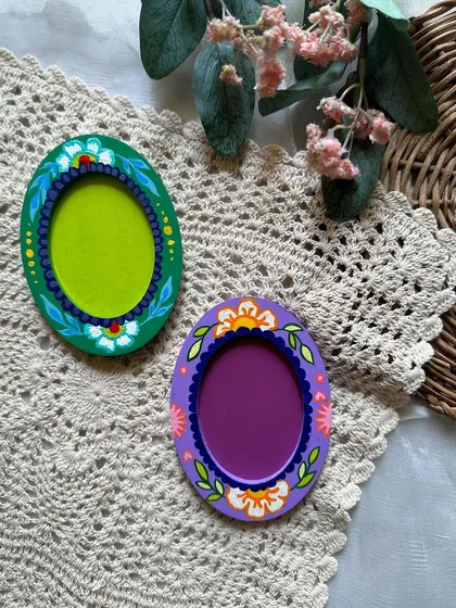 A pair of oval photo frame magnets, each with a unique floral design.