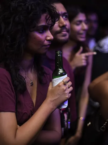 A quiet moment in the crowd, with a patron enjoying her drink and the music.