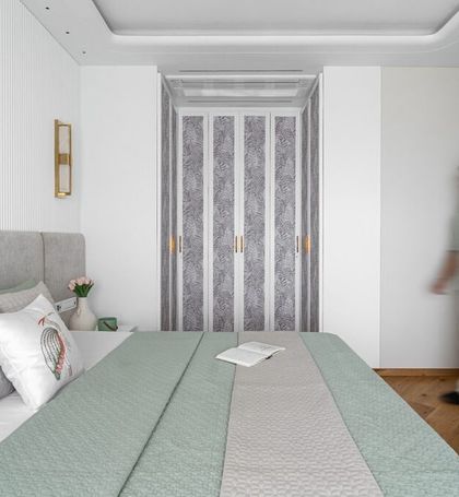 This bedroom uses a palette of sage green and soft grey to create a tranquil atmosphere. The patterned folding wardrobe doors add a unique textural element to the otherwise minimalist design.