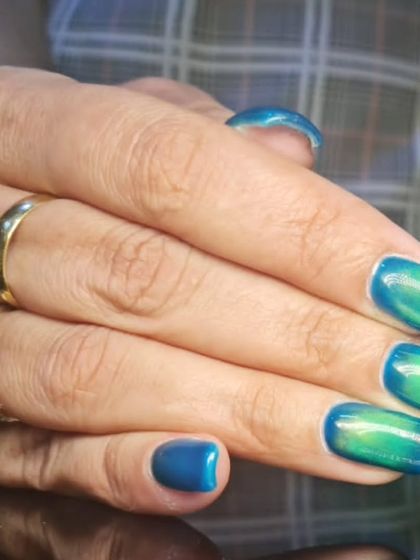 A mesmerizing blue and green color-shifting polish on square nails, creating an aquatic, mermaid-like effect.