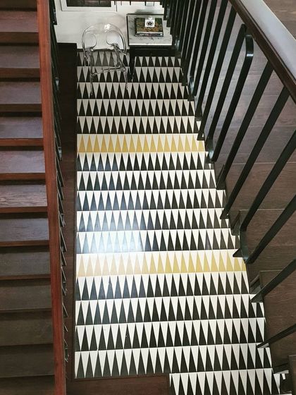 On this staircase, we used a bold triangular tile pattern to break the simplicity of the wood and add character. The geometric design in black, white, and gold creates a stunning visual effect, turning the staircase into a feature element of the home.