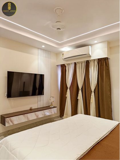 A view of the master bedroom at Uninav Bliss, showing the floating TV unit and elegant two-toned curtains. The design is clean and minimal, maximizing the sense of space while maintaining a cozy feel.
