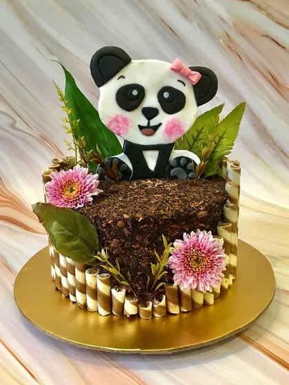 This cute panda cake is nestled in a forest of chocolate shavings and wafer stick bamboo. The hand-cut fondant panda and fresh flowers make it a perfect blend of chocolatey and cute.