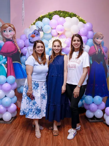 A group of friends poses in front of our "Frozen" themed backdrop, featuring Elsa, Anna, and Olaf. It's a perfect photo opportunity for all the party guests.