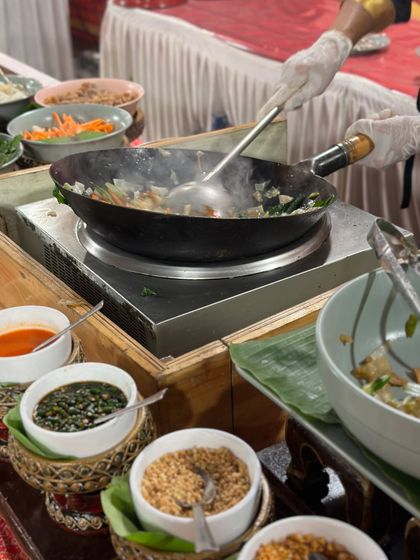 A live Thai wok station in action. The sizzle and aroma of fresh ingredients being stir-fried creates an exciting and authentic atmosphere for guests.