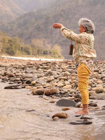 An elder participant offering water to the Ganga, a beautiful act of reverence. My retreats welcome seekers of all ages, honoring the wisdom that each person brings to the circle.