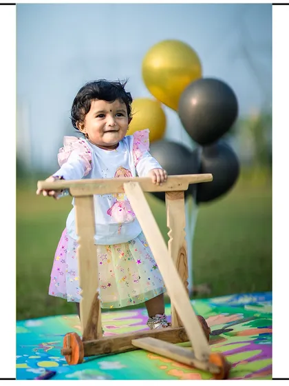 A fun and candid moment from an outdoor first birthday photoshoot. I use props like this wooden walker and balloons to encourage natural play and capture genuine smiles.