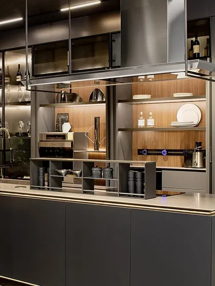 Here, a mix of materials creates a sophisticated look. Smoked glass cabinets, wood shelving, and a stainless steel chimney hood come together to form a kitchen that is rich in texture and high in quality.