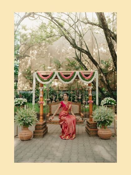 A portrait of the bride, Nikita, seated on a beautifully decorated swing, a classic element of Tamil weddings. The floral decor and her elegant saree create a picturesque scene.