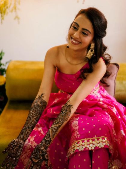 A radiant bride in a stunning pink outfit, her arms beautifully decorated with my intricate mehendi designs.