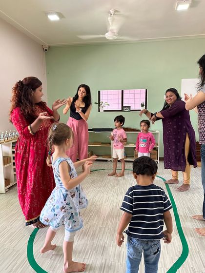 A group of children and teachers engaged in a hand-gesture song during a workshop in Bandra.