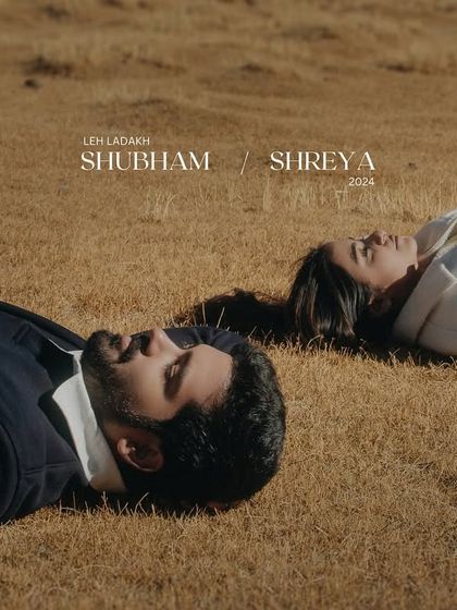 An artistic shot of a couple lying on the sparse grasslands of Ladakh, finding peace and connection under the vast sky. This is a quiet, contemplative pre-wedding portrait.