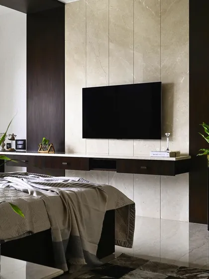 An example of classic, timeless design in a master bedroom. The television is mounted on a wall of polished Italian marble, flanked by rich, dark veneer panels that conceal wiring and add warmth, creating a clean and luxurious media wall.