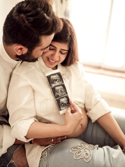 An incredibly sweet and emotional indoor moment. He kisses her cheek as she tears up with joy while looking at their sonogram, a truly precious memory.
