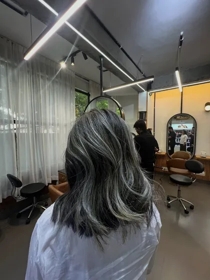 A full view of the salon with the client showcasing her new silver highlights. It gives a great sense of the final look in our space.