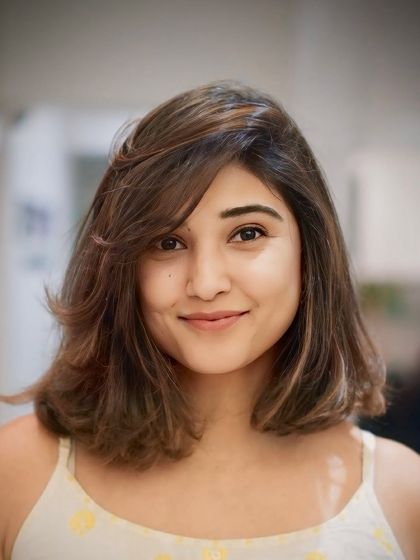 A smiling portrait of our client, happy with her new edgy and modern layered bob haircut.