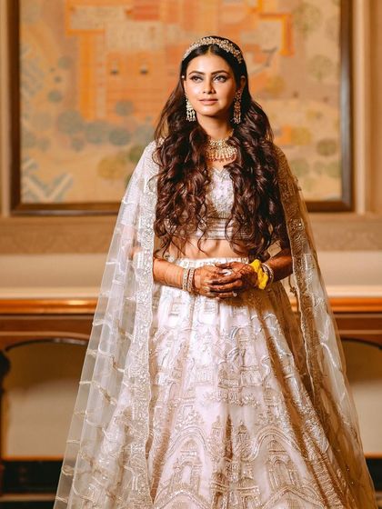 A full-length portrait of the bride, showcasing her stunning white and silver lehenga for the Sangeet.