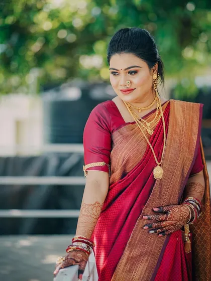 A classic portrait of a Maharashtrian bride in a rich red saree. The natural outdoor lighting and her gentle pose create a timeless and elegant image.