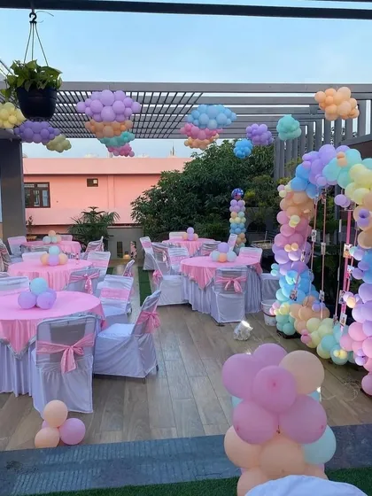 A fun Peppa Pig theme on a rooftop terrace, showing themed table settings and pastel balloon clouds hanging from the ceiling.