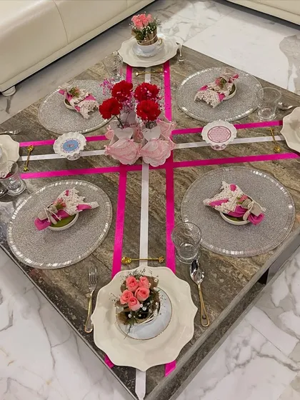An overhead view of the pink ribbon-themed tablescape, designed for a special gathering. The crisscrossing pink and white ribbons create a bold, graphic element on the table, tying all the place settings together.