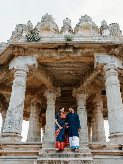 A romantic shot of the couple on the steps of the Melkote temple. The low angle and grand architecture create a sense of timelessness and destiny.