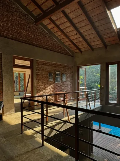 A view from the upper level of The Mango House, looking down towards the pool. The bridge-like corridor connects different parts of the house while maintaining a visual connection to the central living space and the outdoors.