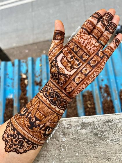 A stunning view of a full arm mehndi design, showcasing a royal procession with peacocks and elephants, set against a backdrop of intricate patterns.