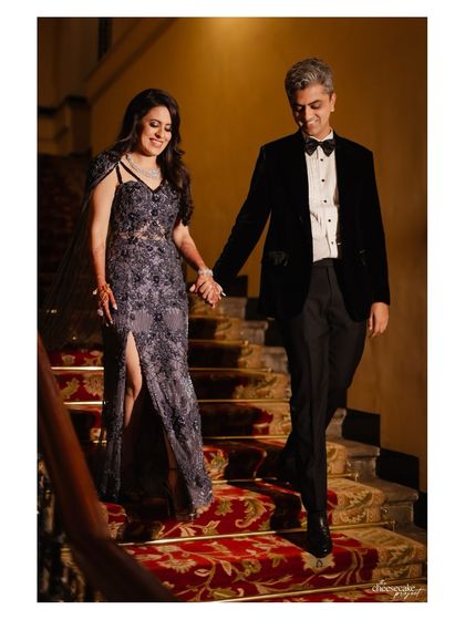 The couple making their way down a grand staircase, a candid moment that feels like a scene from a classic film.